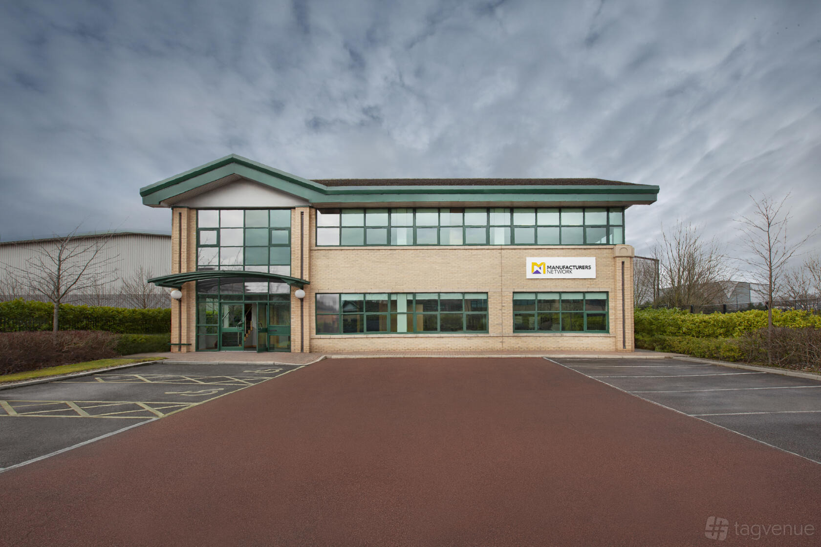 A meeting centre with large windows, brick exterior, and onsite parking at Manufacturers Network.