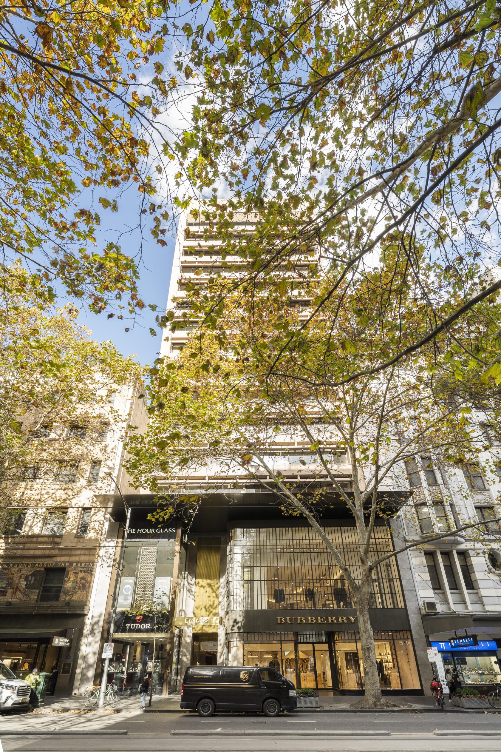 An office building with large upper balconies and leafy trees in front at Sector Serviced Offices- Collins Street.