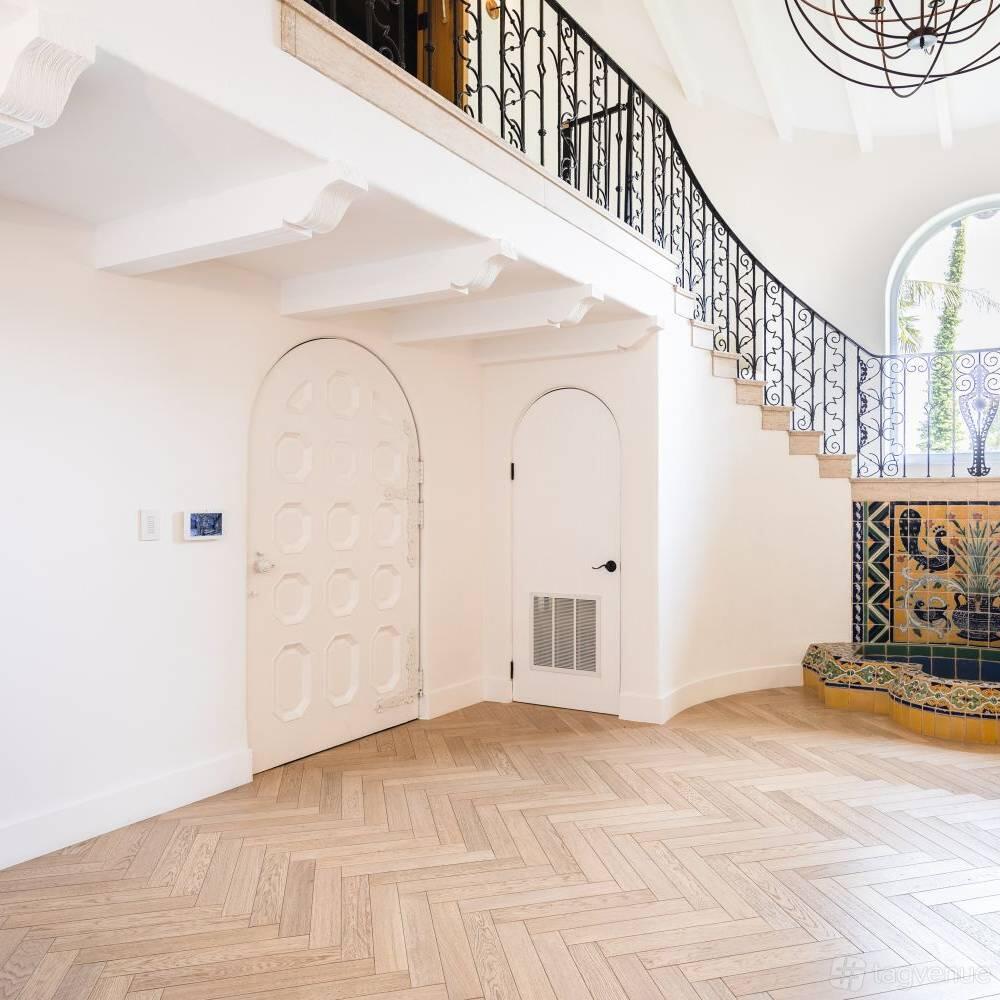 A house with arched doorways, herringbone wood floors, and a staircase with decorative tile at Spanish Estate.