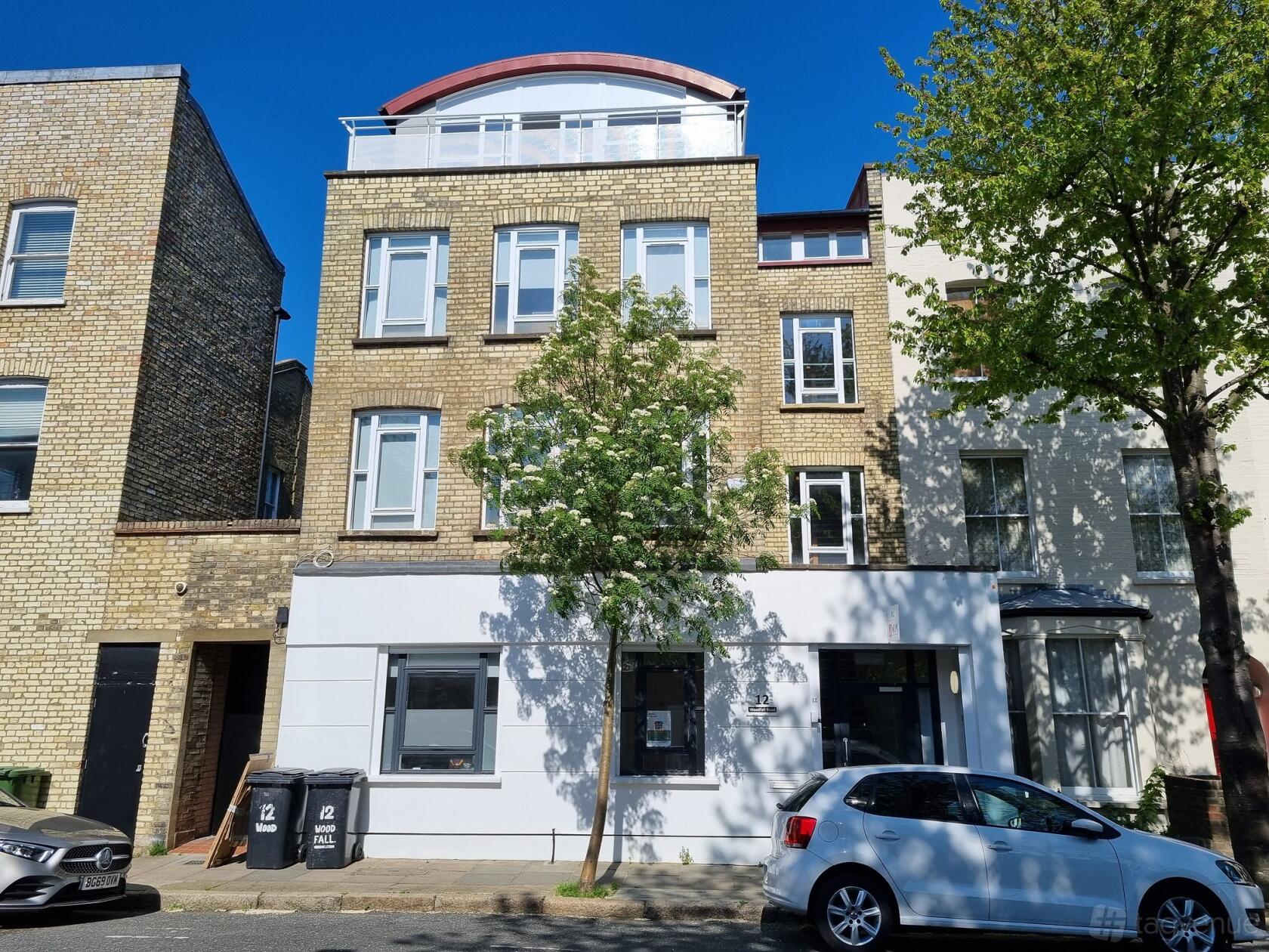 A brick and white facade meeting centre with large windows and a tree-lined street at Strides HCC.