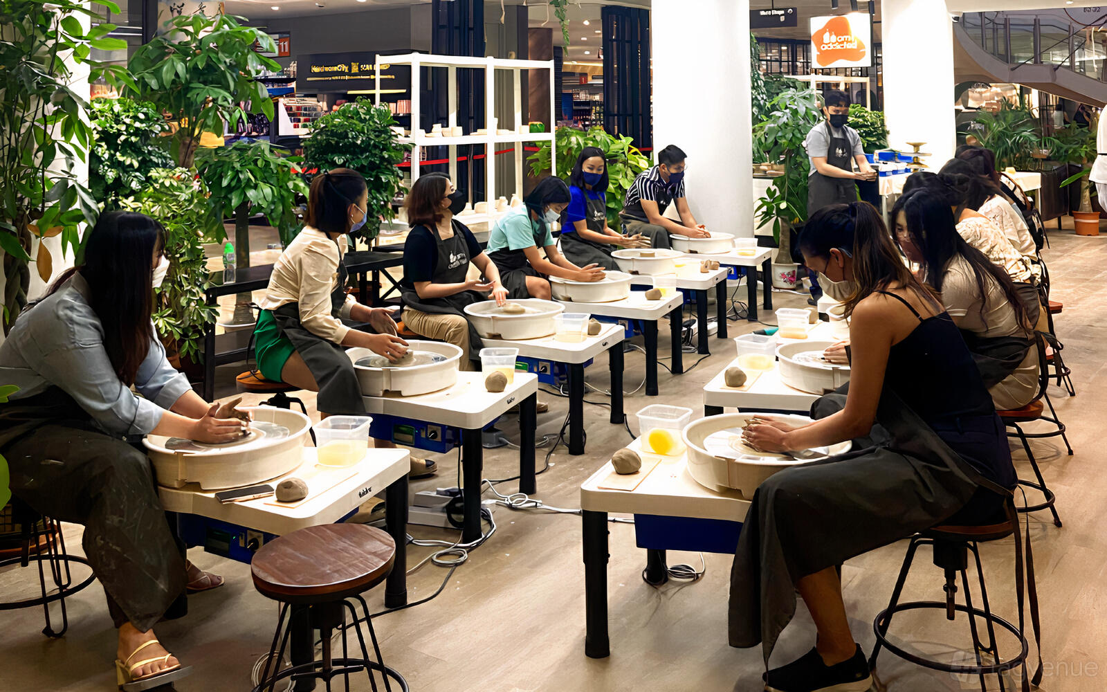 An event space with pottery wheels arranged in a row and people sculpting clay at Am I Addicted Korean Pottery Studio.