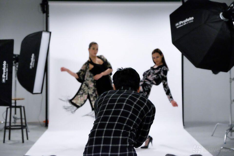A recording studio with a white cyclorama backdrop, studio lights, and models posing at The Hive Studios.