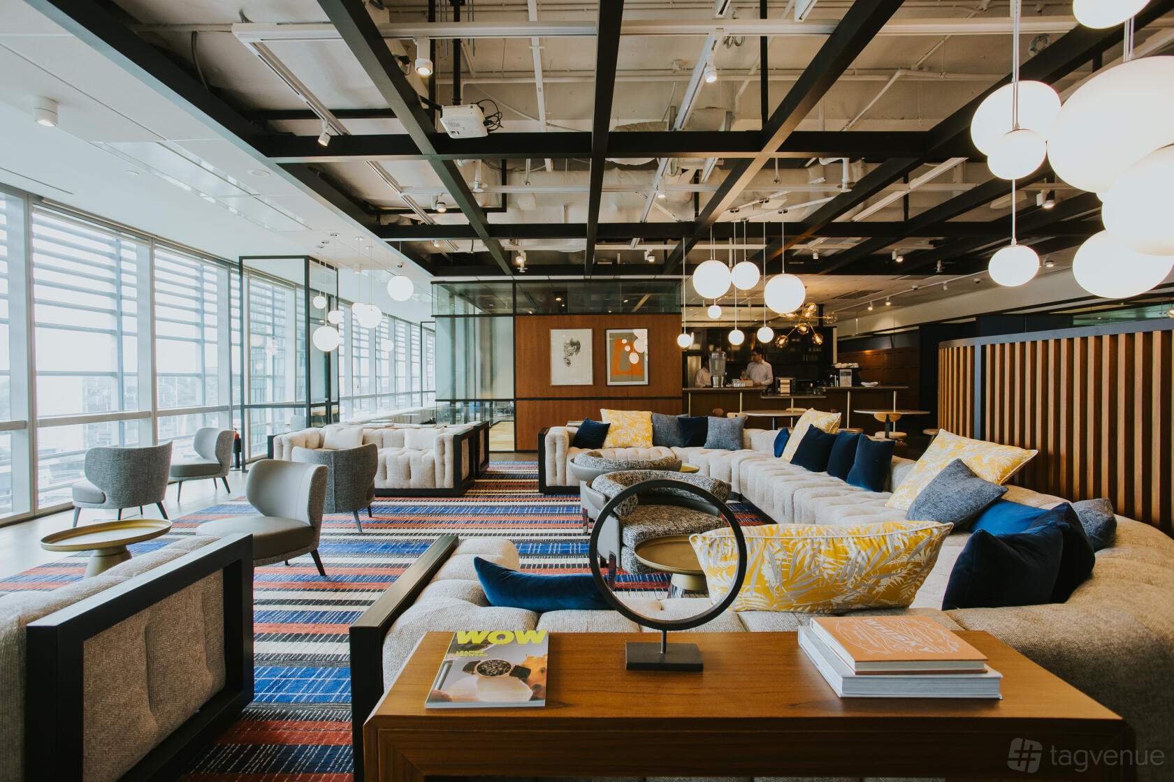 A coworking space with floor-to-ceiling windows, lounge seating, and contemporary lighting at The Great Room - One George Street.