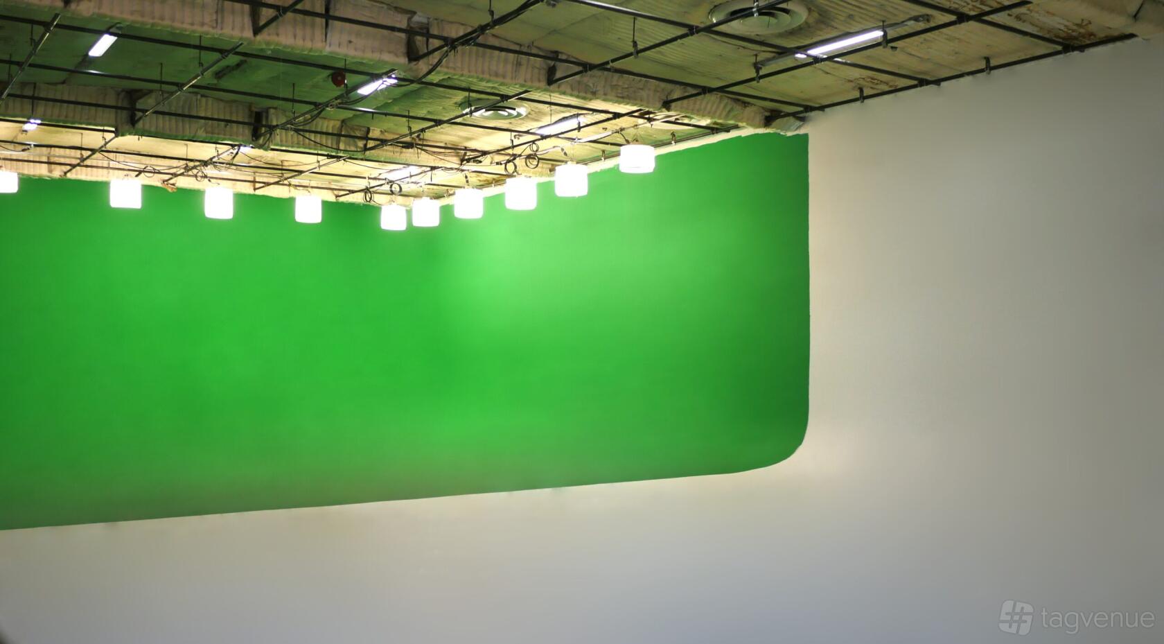 A photo studio with a large green cyclorama wall and overhead pendant lighting at BLT STUDIOS.