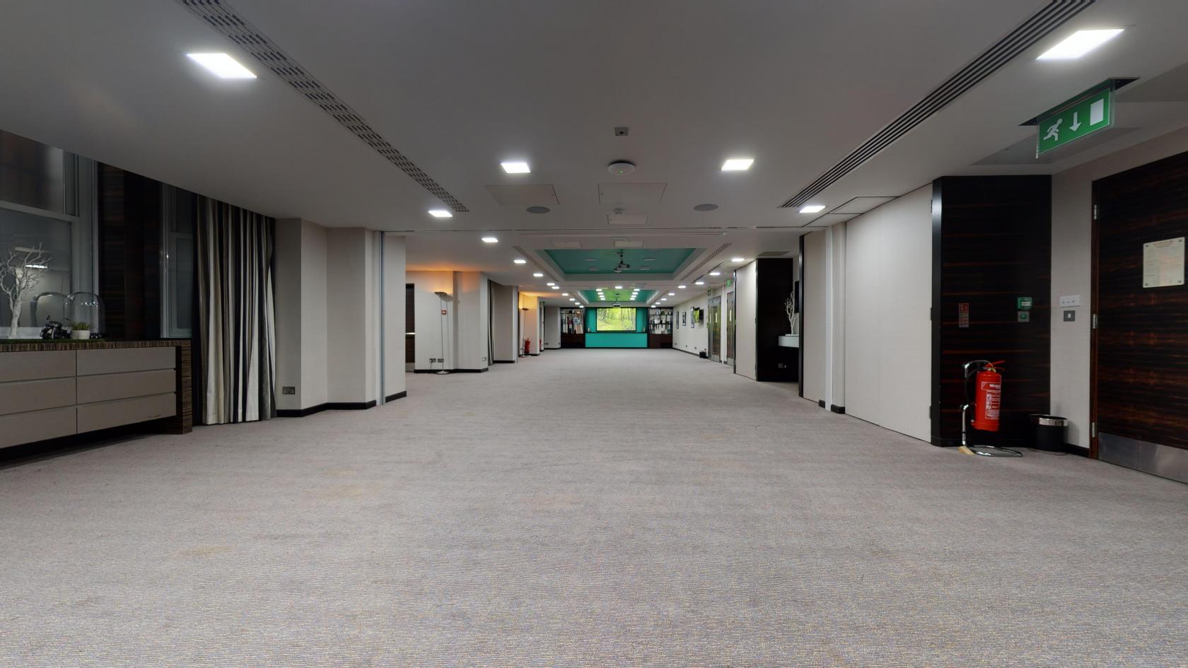 A hotel event space with carpeted floors, recessed ceiling lights, and large windows at DoubleTree by Hilton London Kensington.