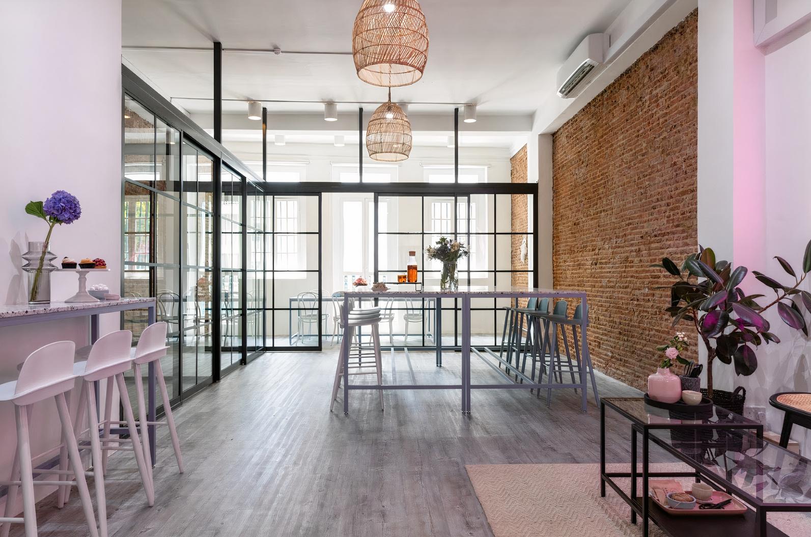 An event venue with exposed brick walls, glass partitions, high tables, and woven pendant lights at Host Events Pte Ltd.