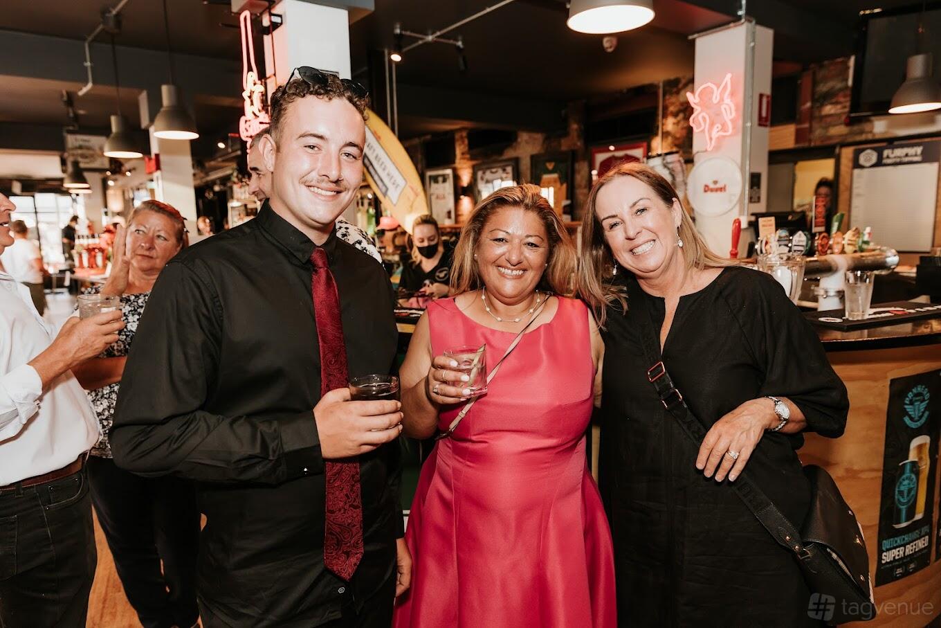 A bar in a pub with high ceilings, exposed brick accents, and neon signage behind the counter at The Quarry Hotel.