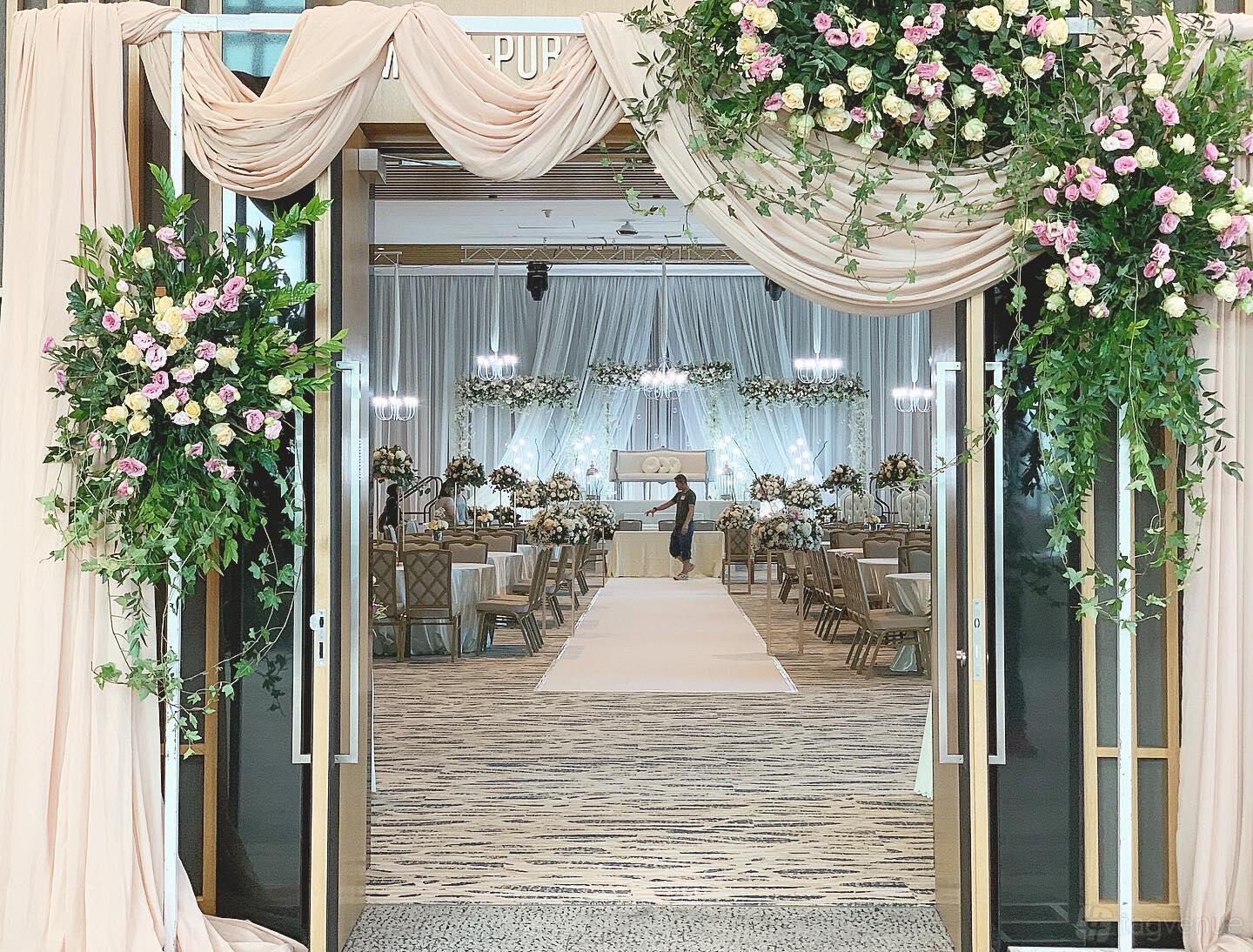 An event venue with draped fabric, floral arrangements, and an aisle leading to a decorated stage at Bay Laurel.