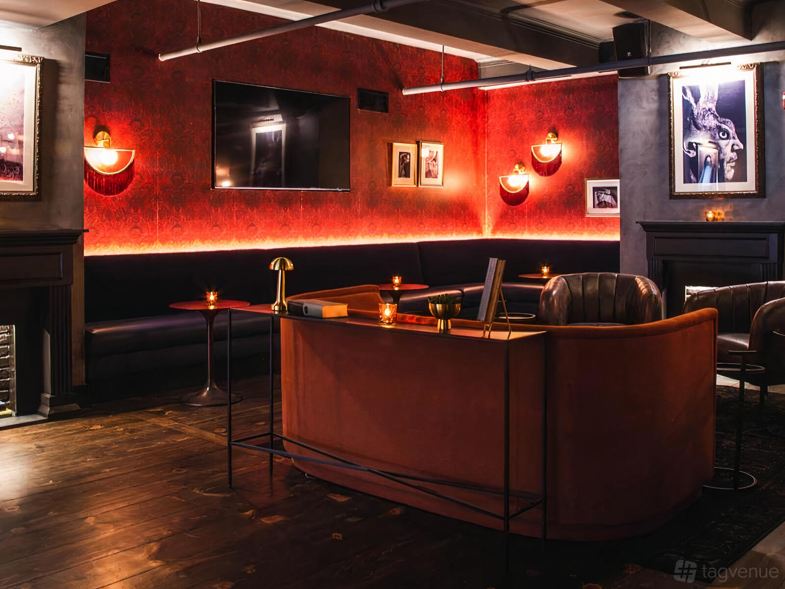 A function room with red textured walls, leather sofas, wall sconces, and framed art at 5th and Mad.