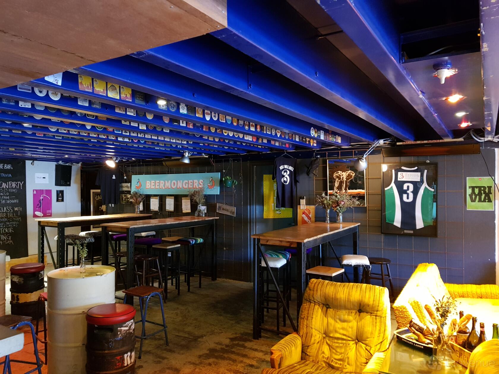 A brewery bar with high tables, bar stools, colorful ceiling beams, and sports memorabilia at 3 Ravens Brewery.