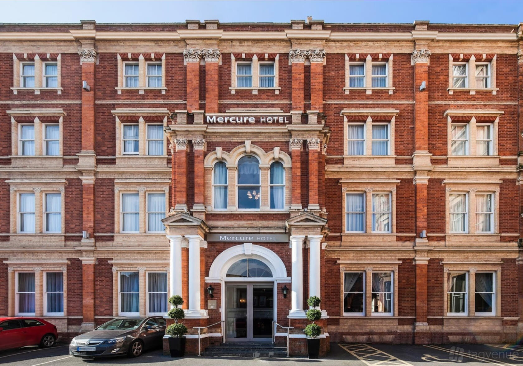 A historic hotel exterior with ornate brickwork, arched doorway, and tall sash windows at Mercure Exeter Rougemont Hotel.