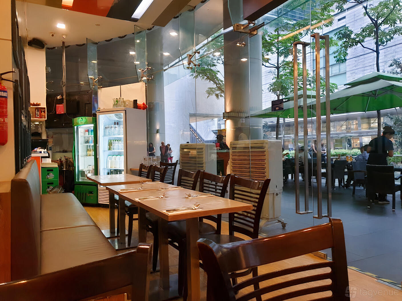A cafe with glass walls, wooden tables and chairs, and an outdoor seating area at Anglo Indian Cafe & Bar - Shenton Way.