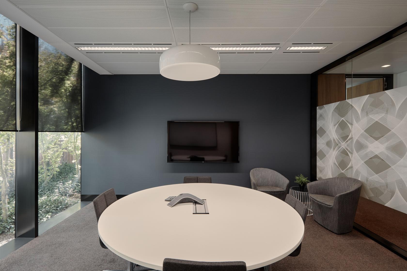 A meeting room with a round table, video conferencing equipment, and floor-to-ceiling windows at Flex by ISPT at 4 National Circuit.