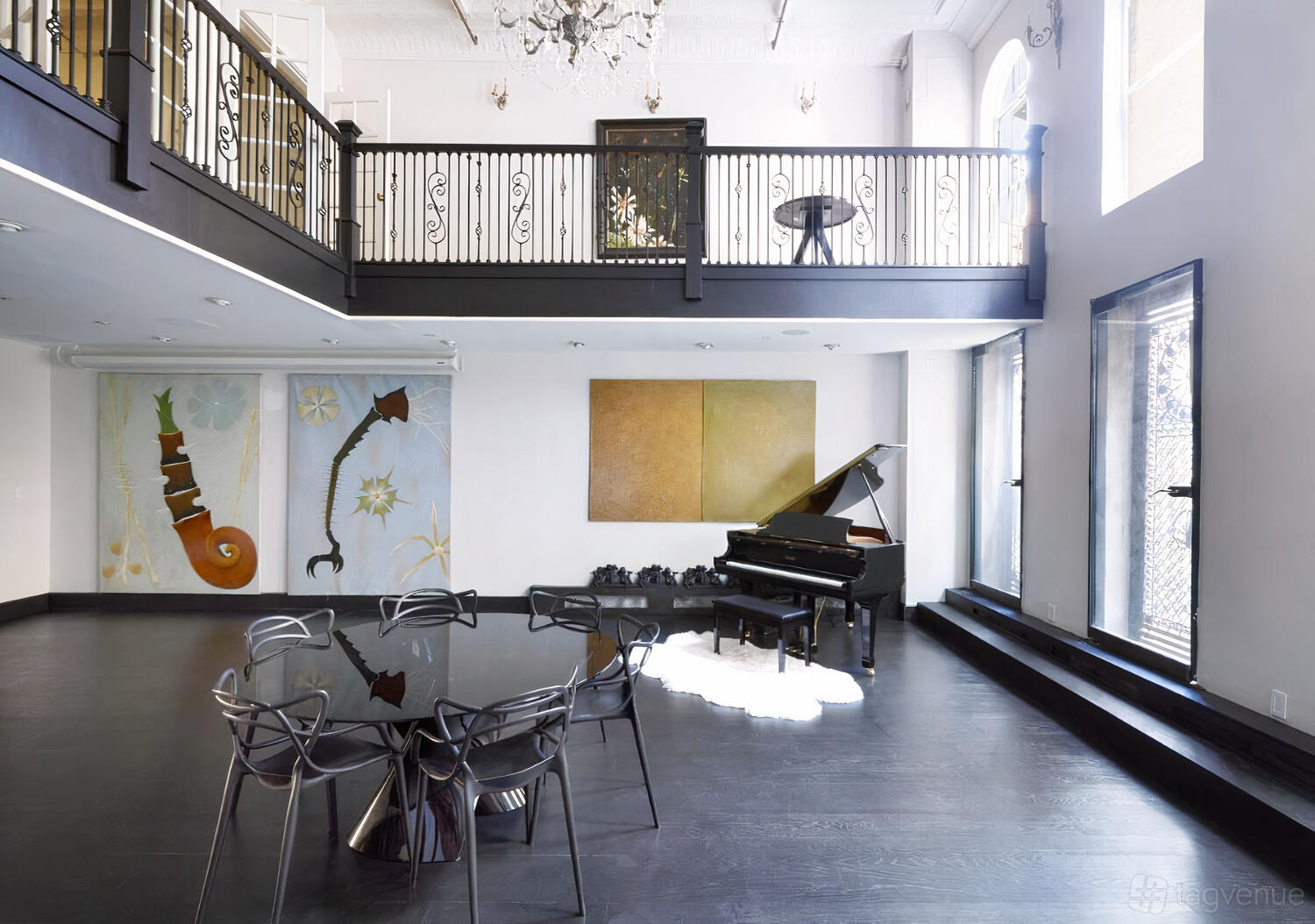 An event venue with a grand piano, modern art on white walls, and a glass table with chairs at Casa Estrella.