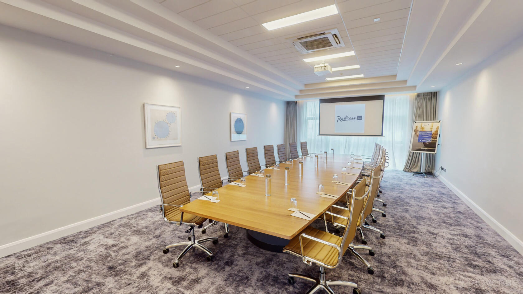 A meeting room with a long wooden conference table, ergonomic chairs, and floor-to-ceiling windows at Radisson Blu Hotel, Dublin Airport.