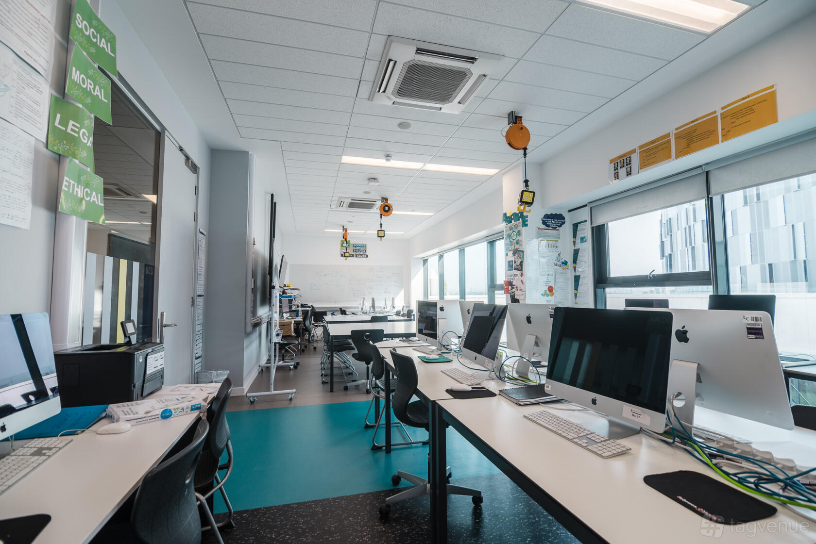 A coworking space with rows of computers, large windows, and wall-mounted whiteboards at London Academy of Excellence Tottenham.