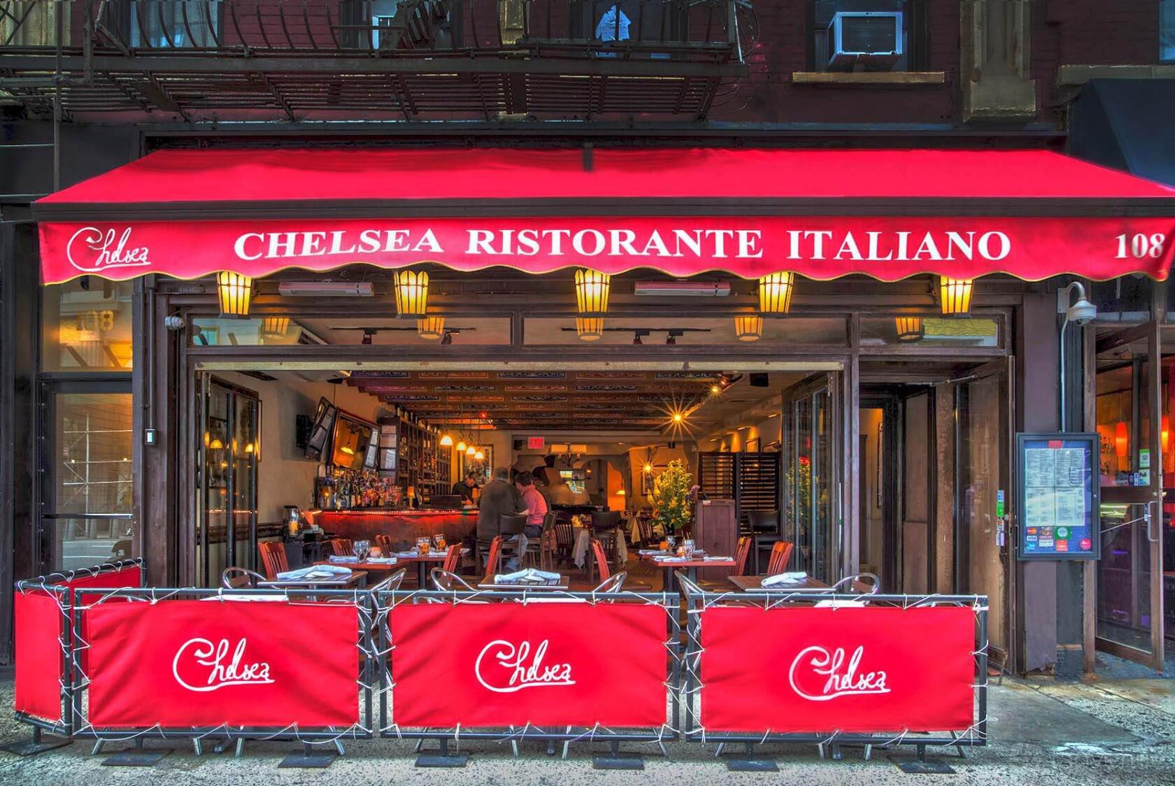 A restaurant with red awnings, open storefront, and outdoor sidewalk seating at Chelsea Ristorante Italiano.
