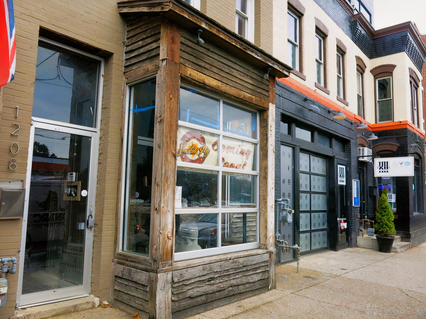 A restaurant storefront with rustic wood framing, large windows, and a street entrance at Smokin' Pig.