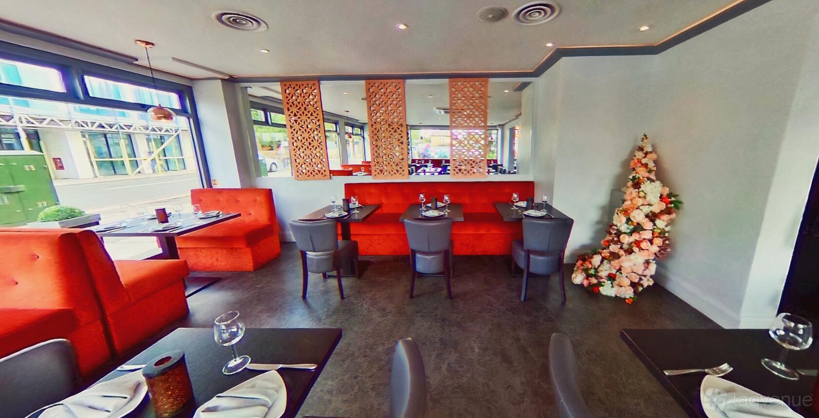 An event space in a restaurant with orange booth seating, decorative wall panels, and a floral arrangement at Laguna Restaurant.