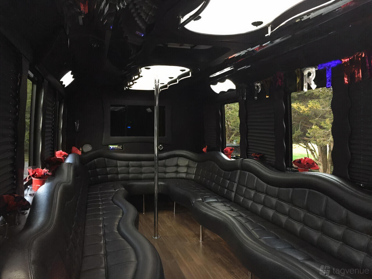 A party bus with black leather wraparound seating, wood floors, tinted windows, and mirrored ceiling panels at Moelimo Limousine & Livery Service.