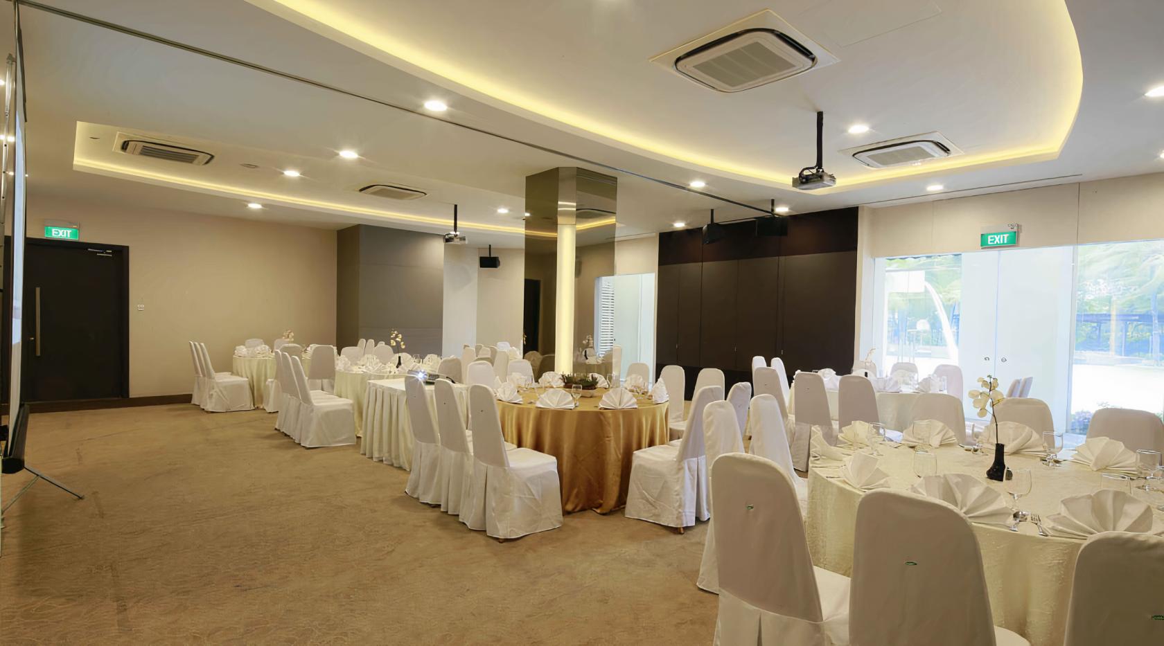 An event space with round tables covered in gold and white linens, banquet chairs, and recessed lighting at The Chevrons.