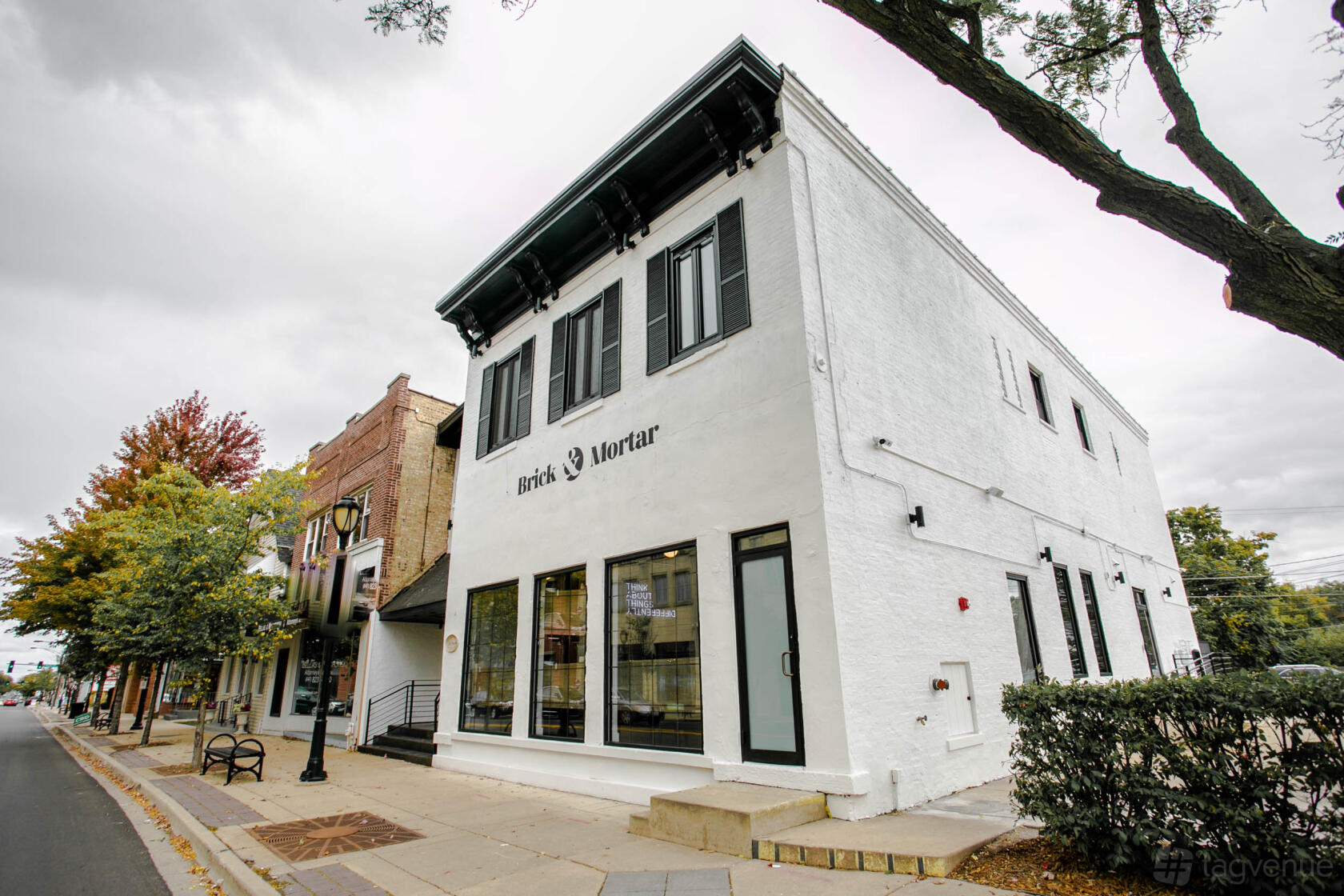 A coworking space with a white painted brick exterior and large front windows at Brick & Mortar.