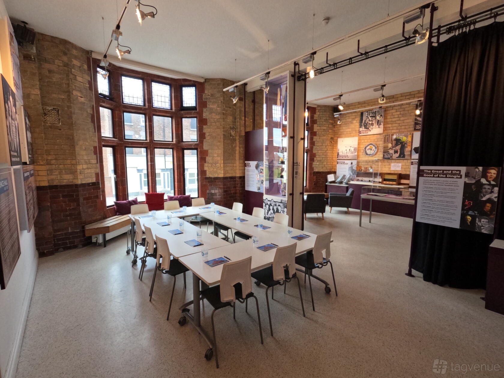 An event space with exposed brick walls, large windows, and white tables with chairs at The Florrie.