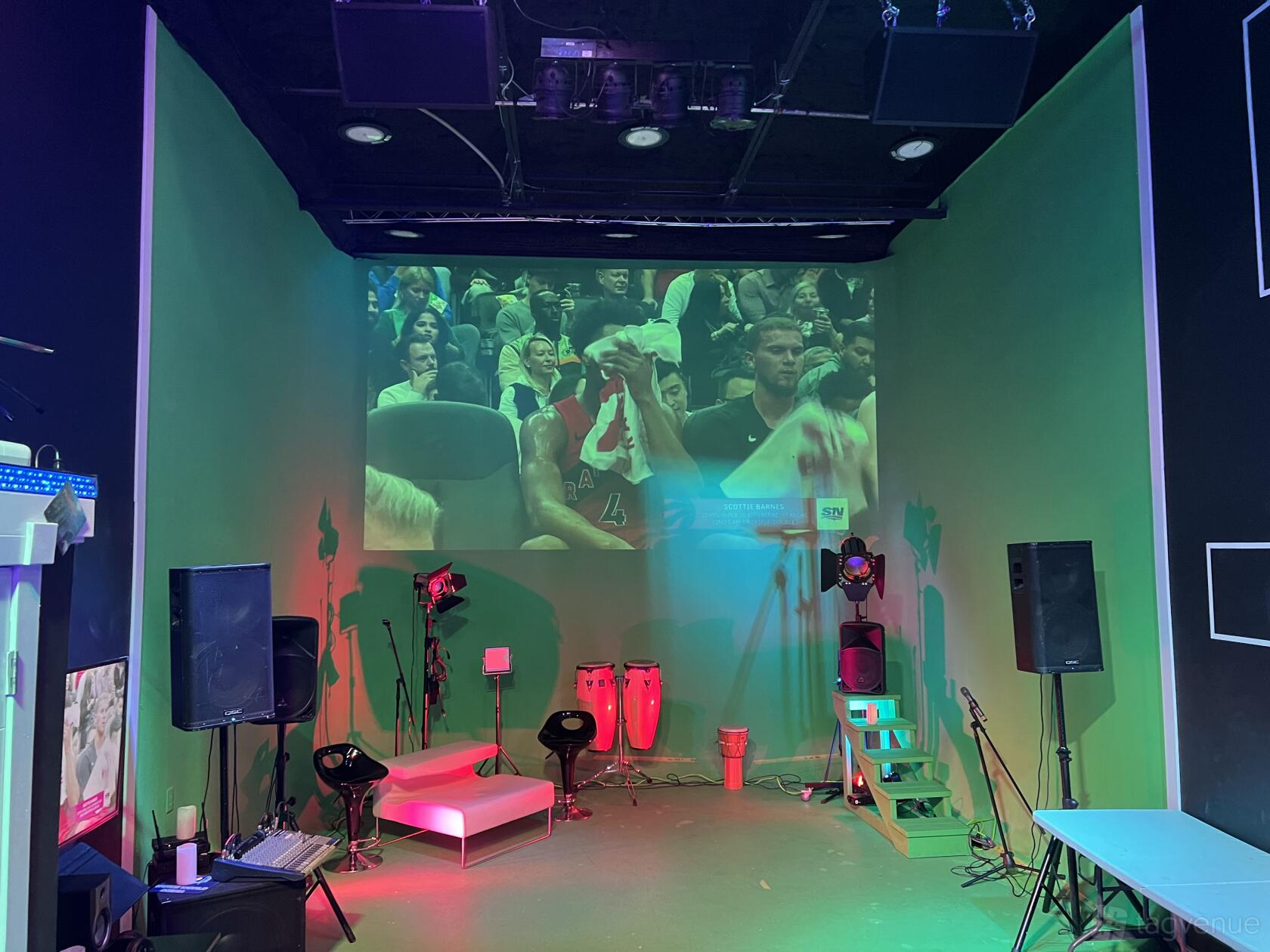 An event venue with green walls, stage lighting, projection screen, and lounge seating at VanceWorldMedia.