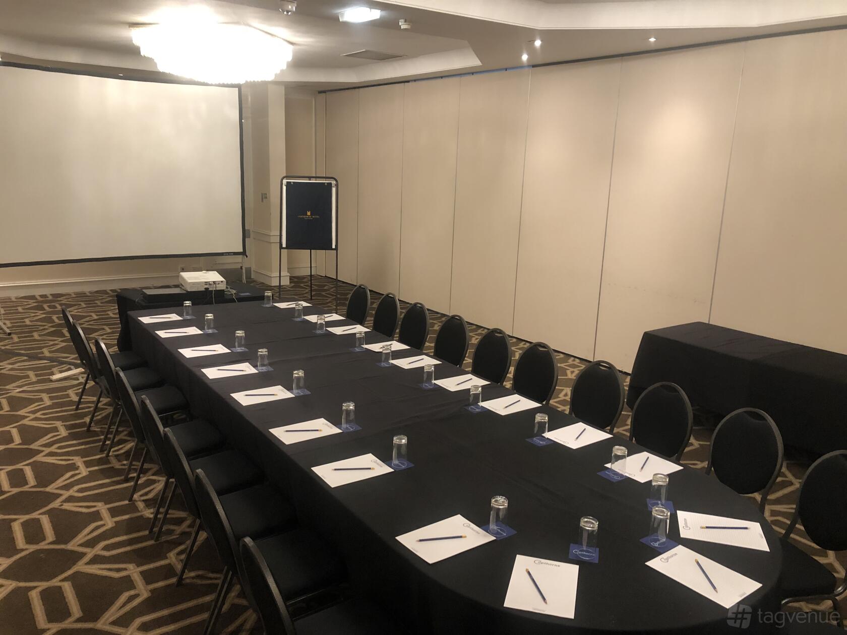 A hotel meeting room with a U-shaped table arrangement, notepads, and a projector at Copthorne Hotel Manchester.
