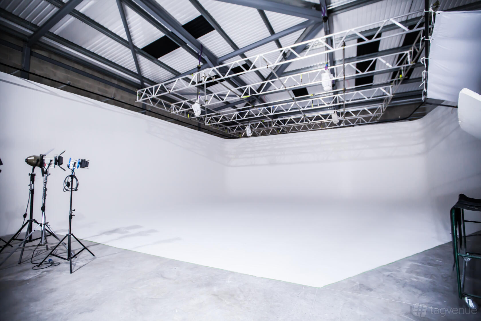 A spacious photo studio with a white cyclorama wall, overhead lighting truss, and studio lights at Foundry Film Studios.