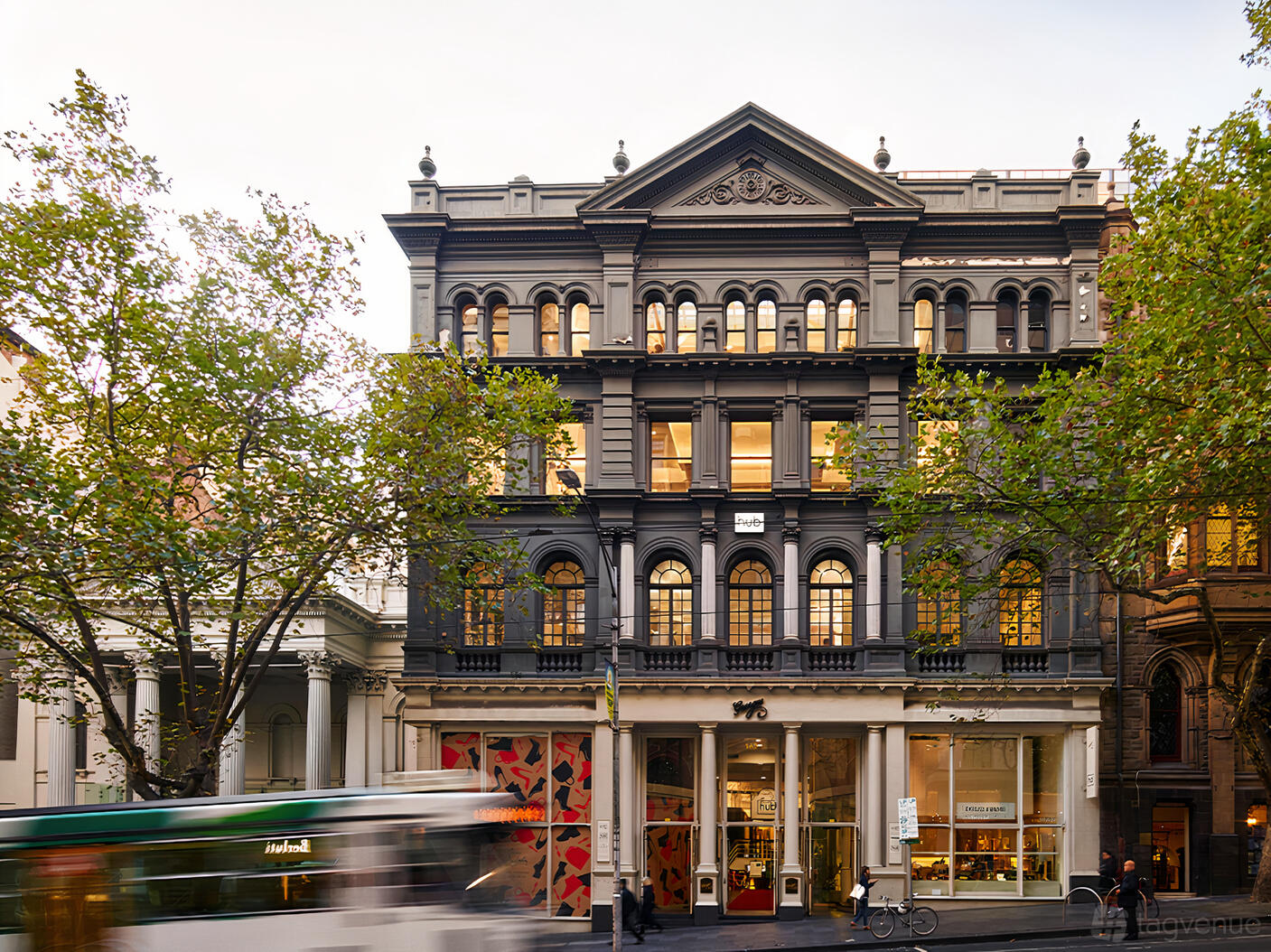 A coworking space in a restored heritage building with tall arched windows and ornate facade at Hub Collins Street.