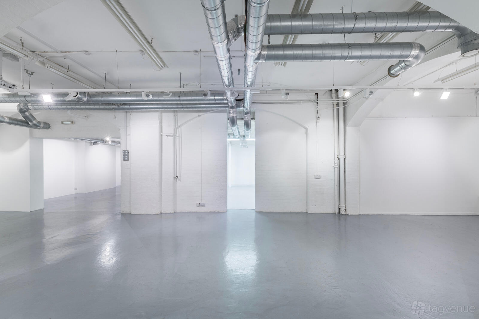 An event venue with polished concrete floors, exposed ductwork, and white walls at Noho Studios.