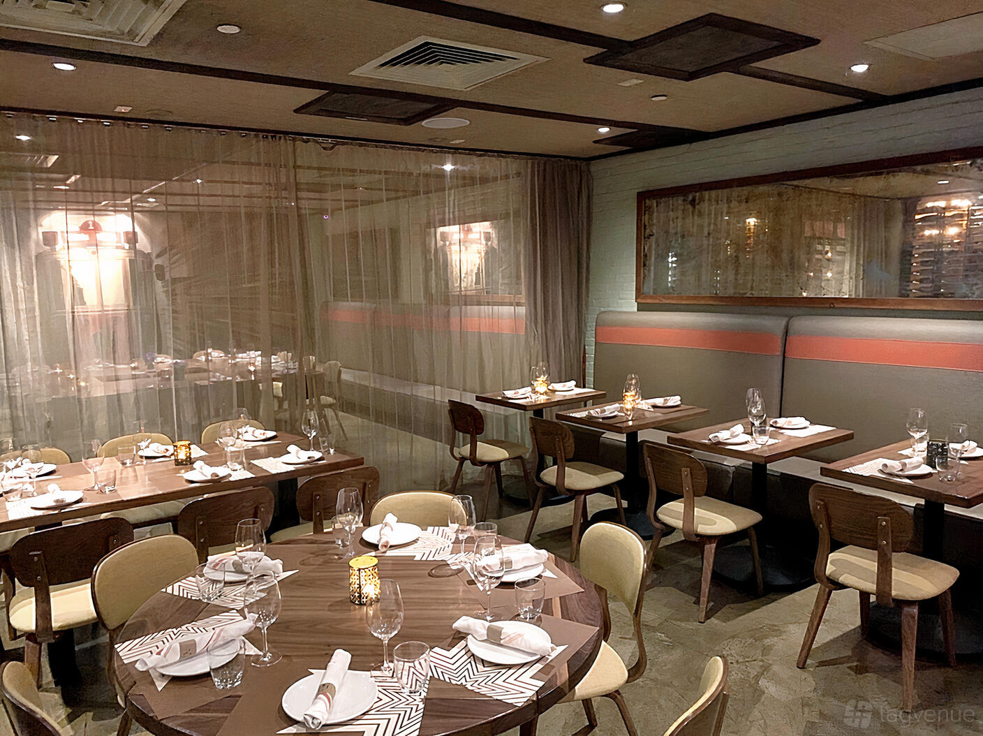 An event space in a restaurant with round and rectangular tables set with napkins and glassware at Pera Soho.