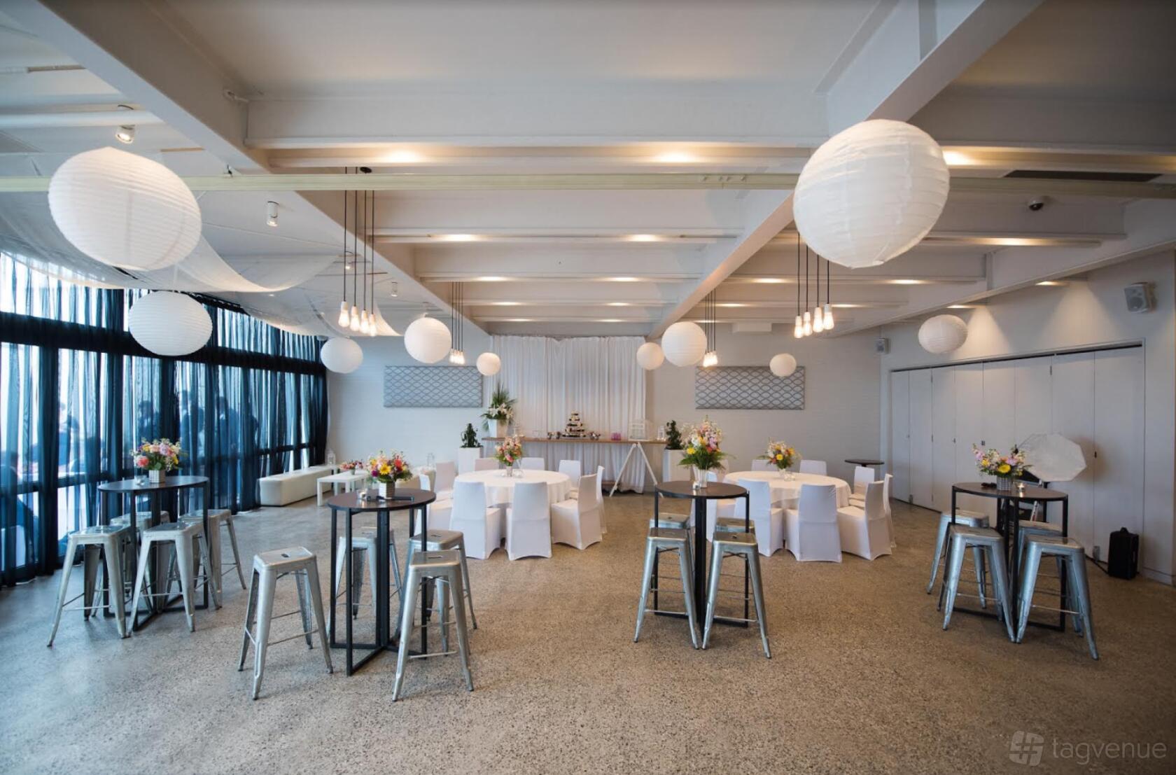 A function room in a restaurant with paper lanterns, high tables, and floor-to-ceiling windows at True South.