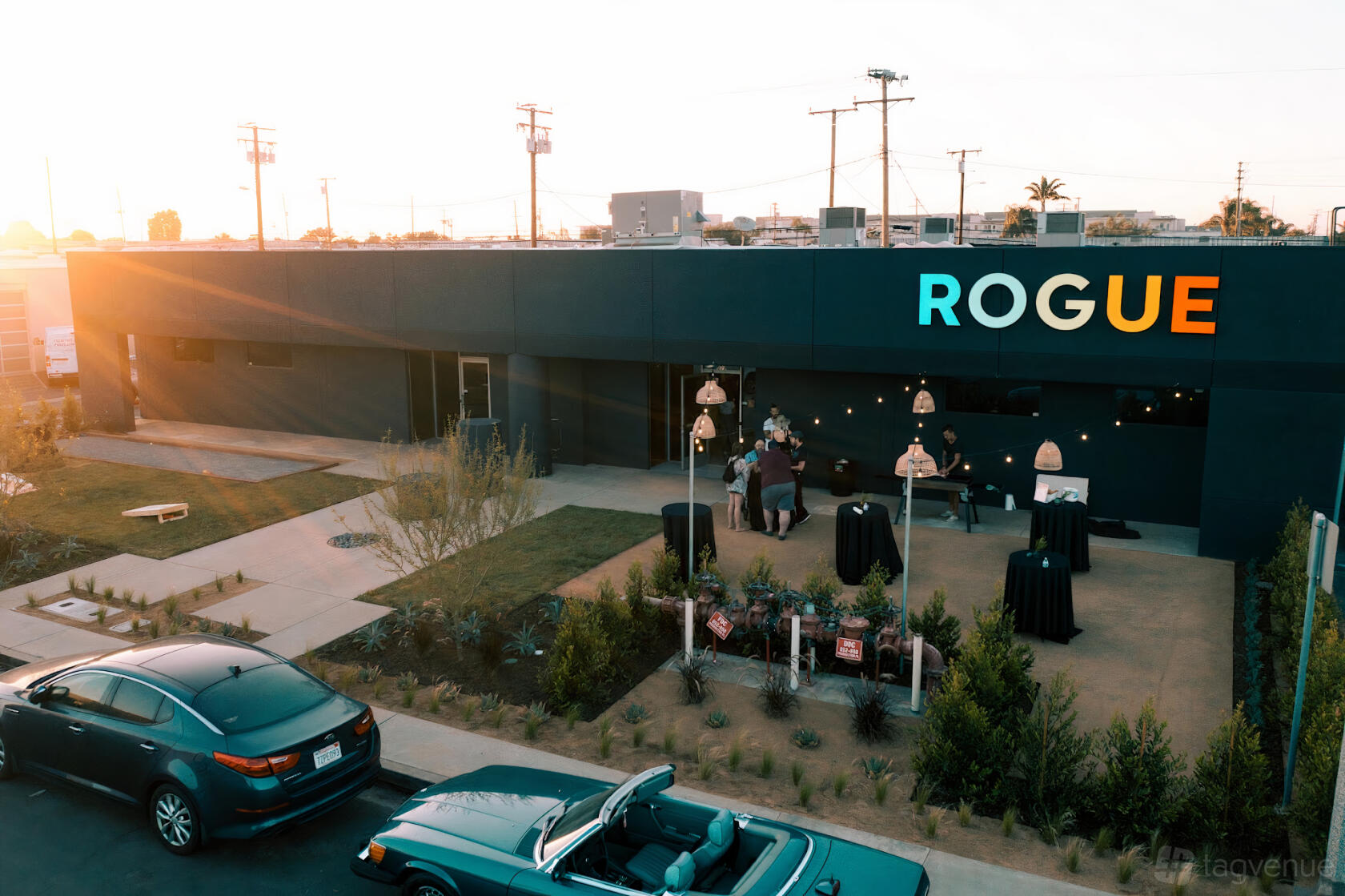 A warehouse venue with a landscaped entrance, outdoor seating, and string lights at Rogue Collective.