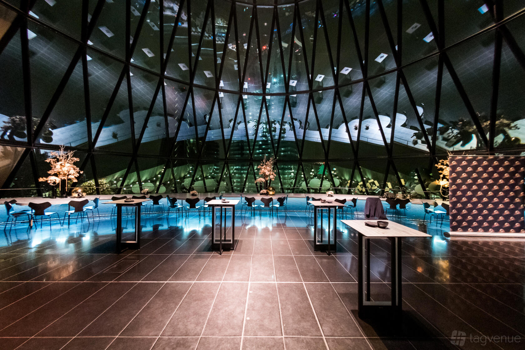 A restaurant with floor-to-ceiling glass windows, skyline views, and cocktail tables at Searcys at The Gherkin.