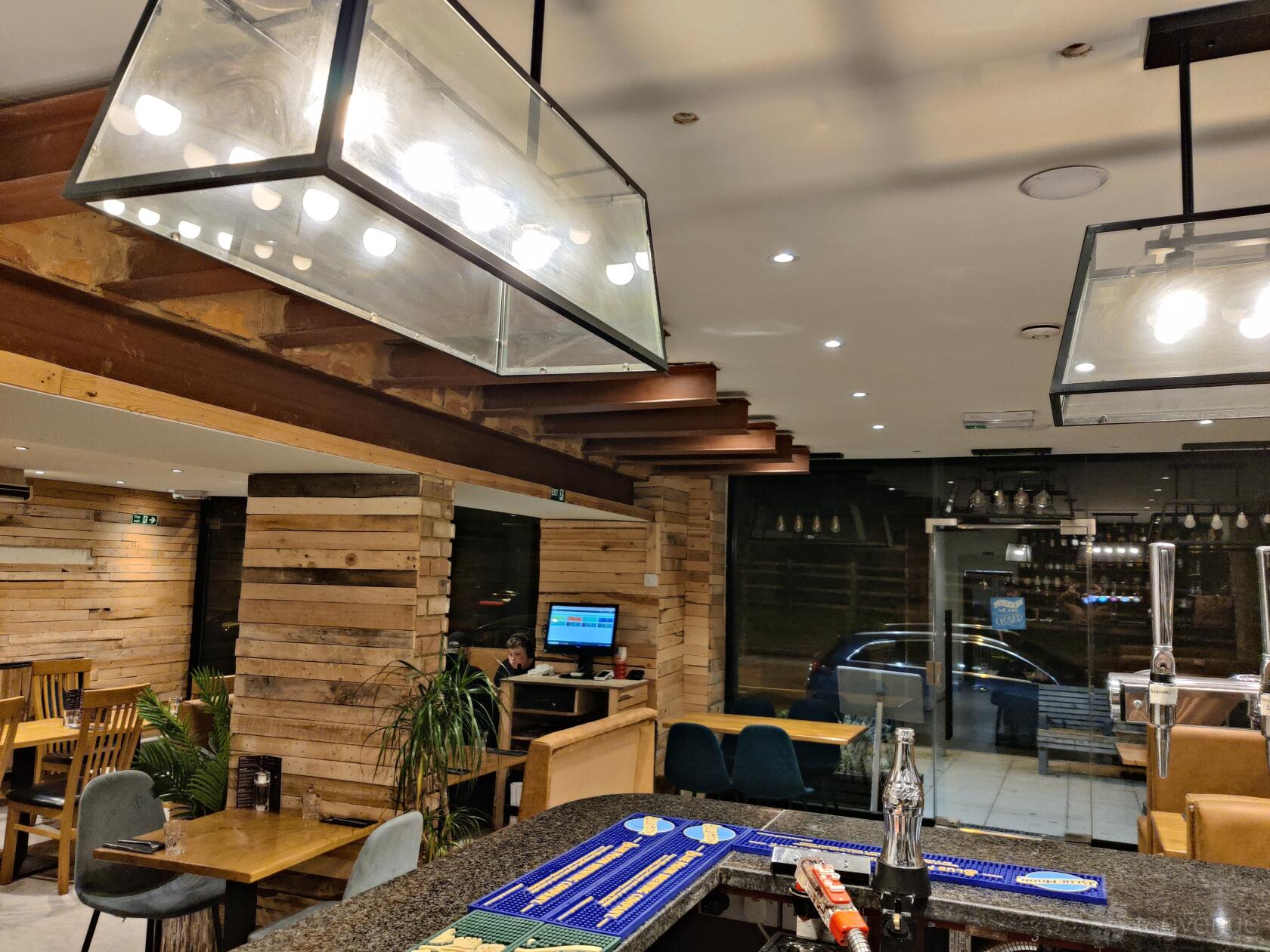 An event space in a restaurant with wood-paneled walls, ceiling beams, and pendant lighting at Smokin' Grill Steakhouse Kenley.