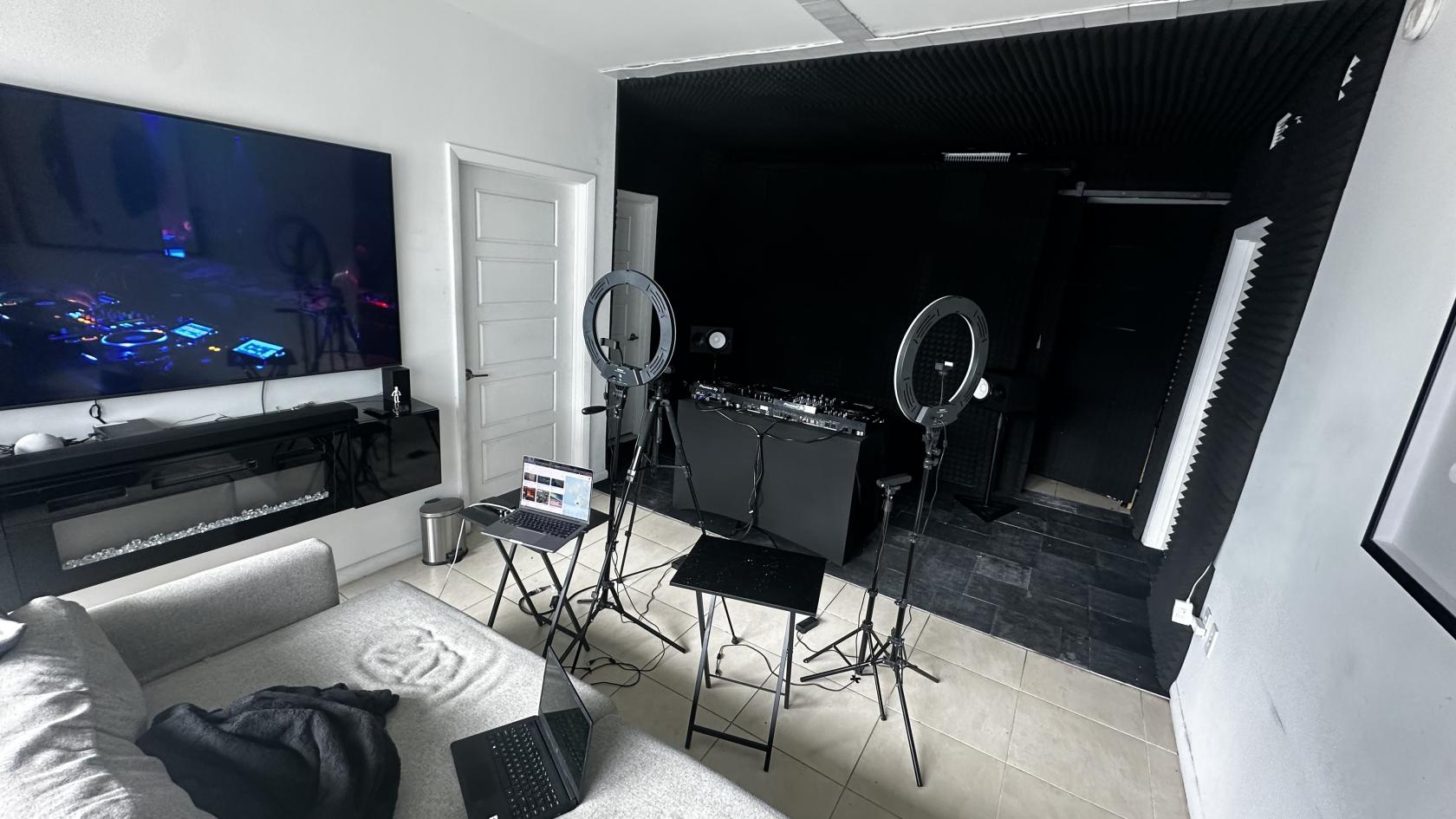 A music studio with DJ equipment, two ring lights, a laptop, and soundproofed black walls at Music Studio for DJs.