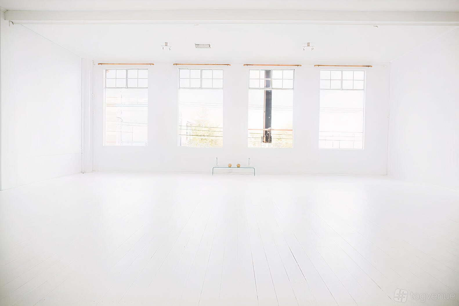 An event venue with white wooden floors, tall windows, and minimalist decor at Prana House.