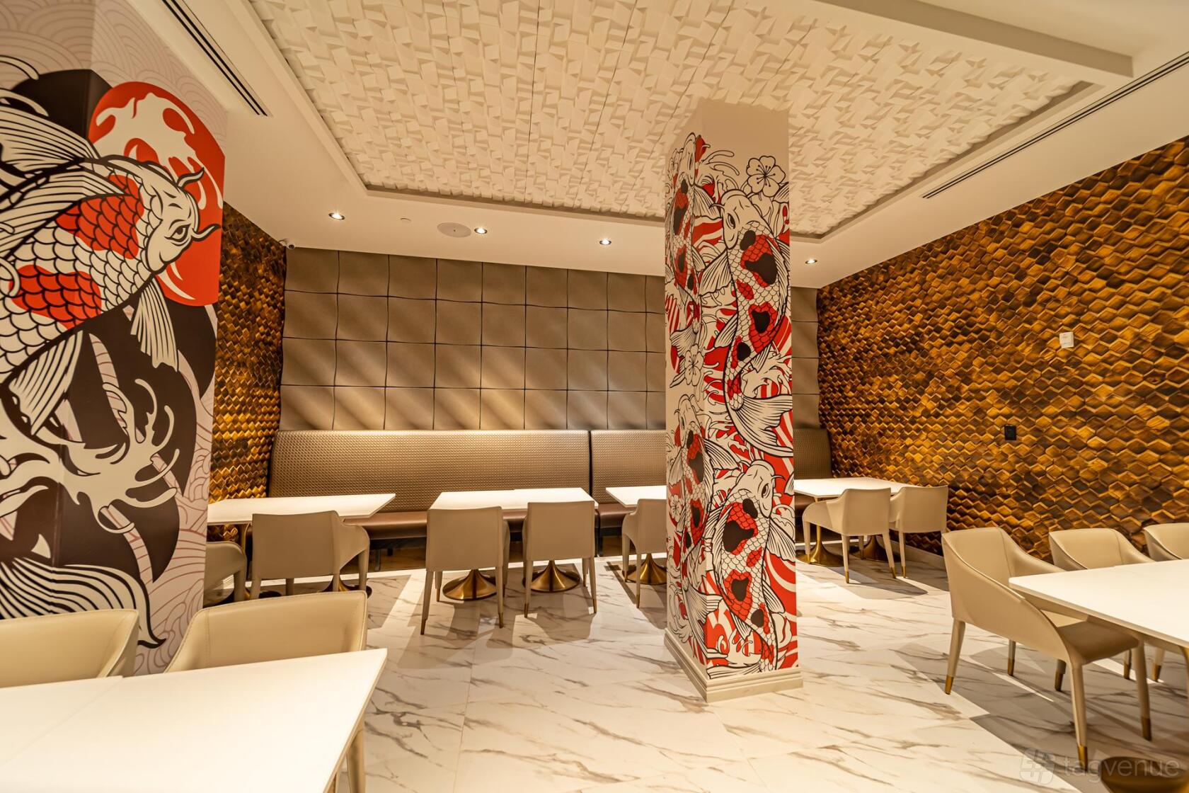 A dining room with white marble floors, koi fish murals on columns, and gold textured accent walls at Fushimi Times Square.
