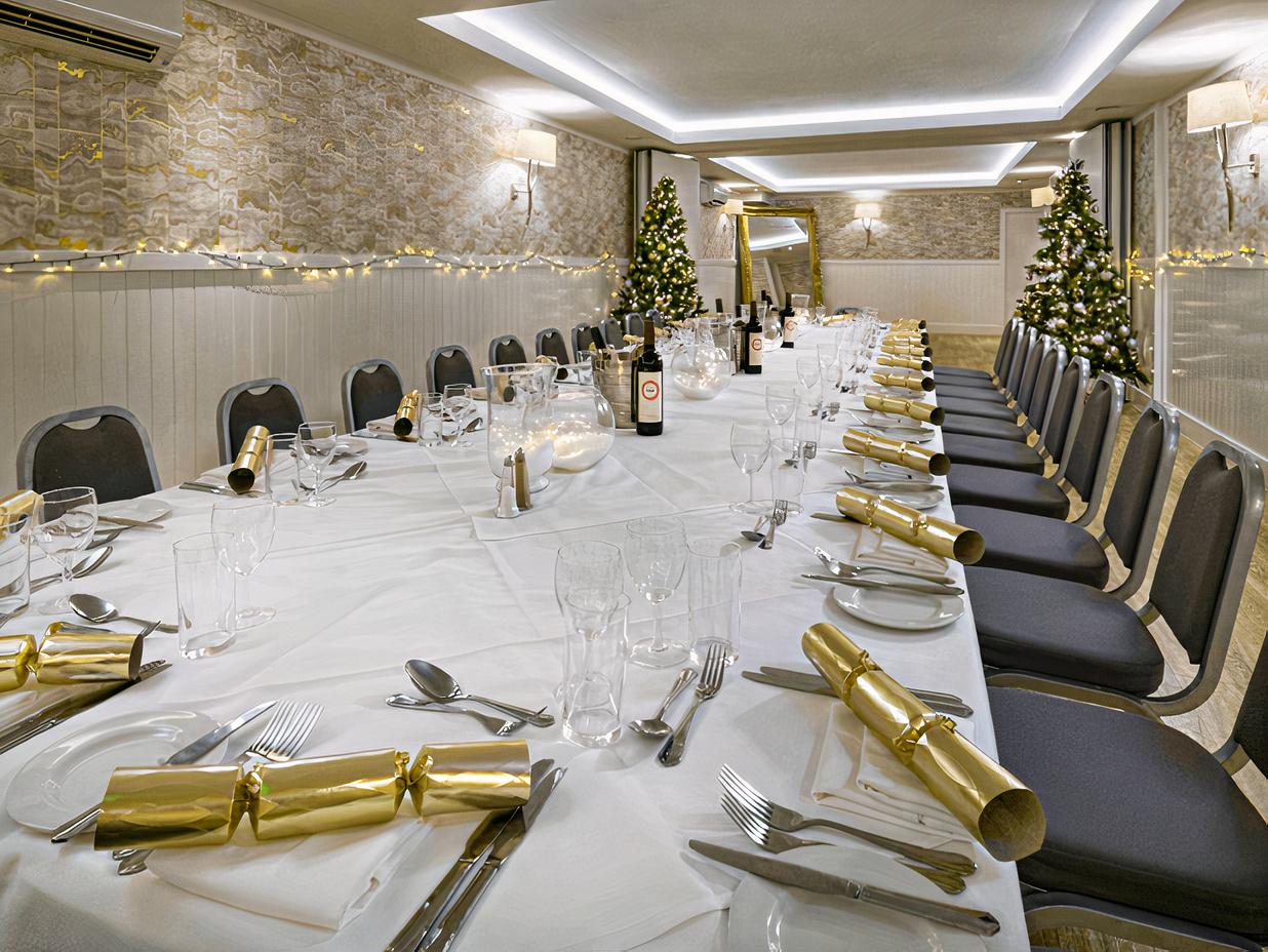 An event space with white table linens, festive gold decorations, and Christmas trees at Bristol Harbour Hotel.