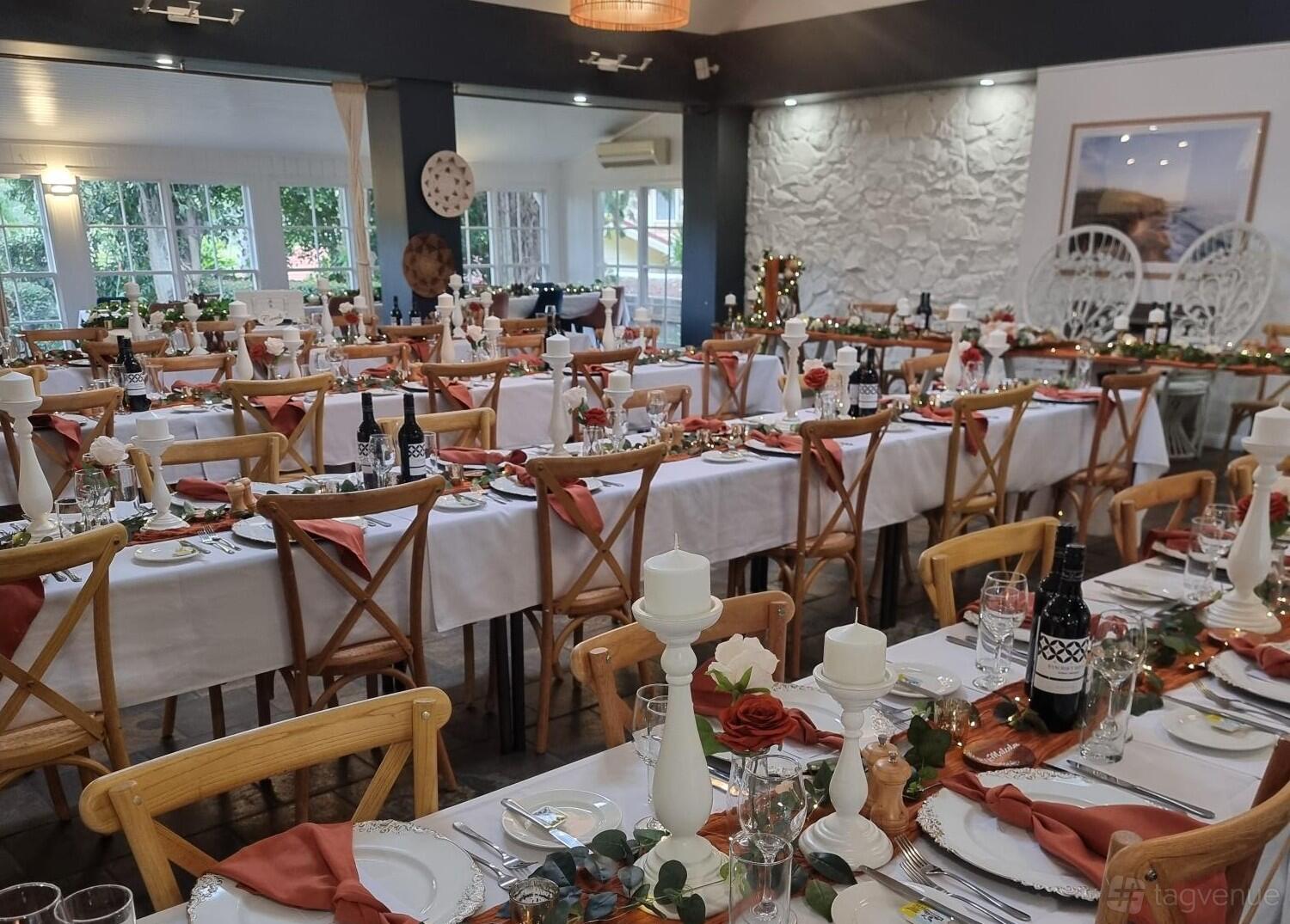 A restaurant with banquet-style tables adorned with white linens, red napkins, and decorative greenery at Mercure Gerringong Resort.