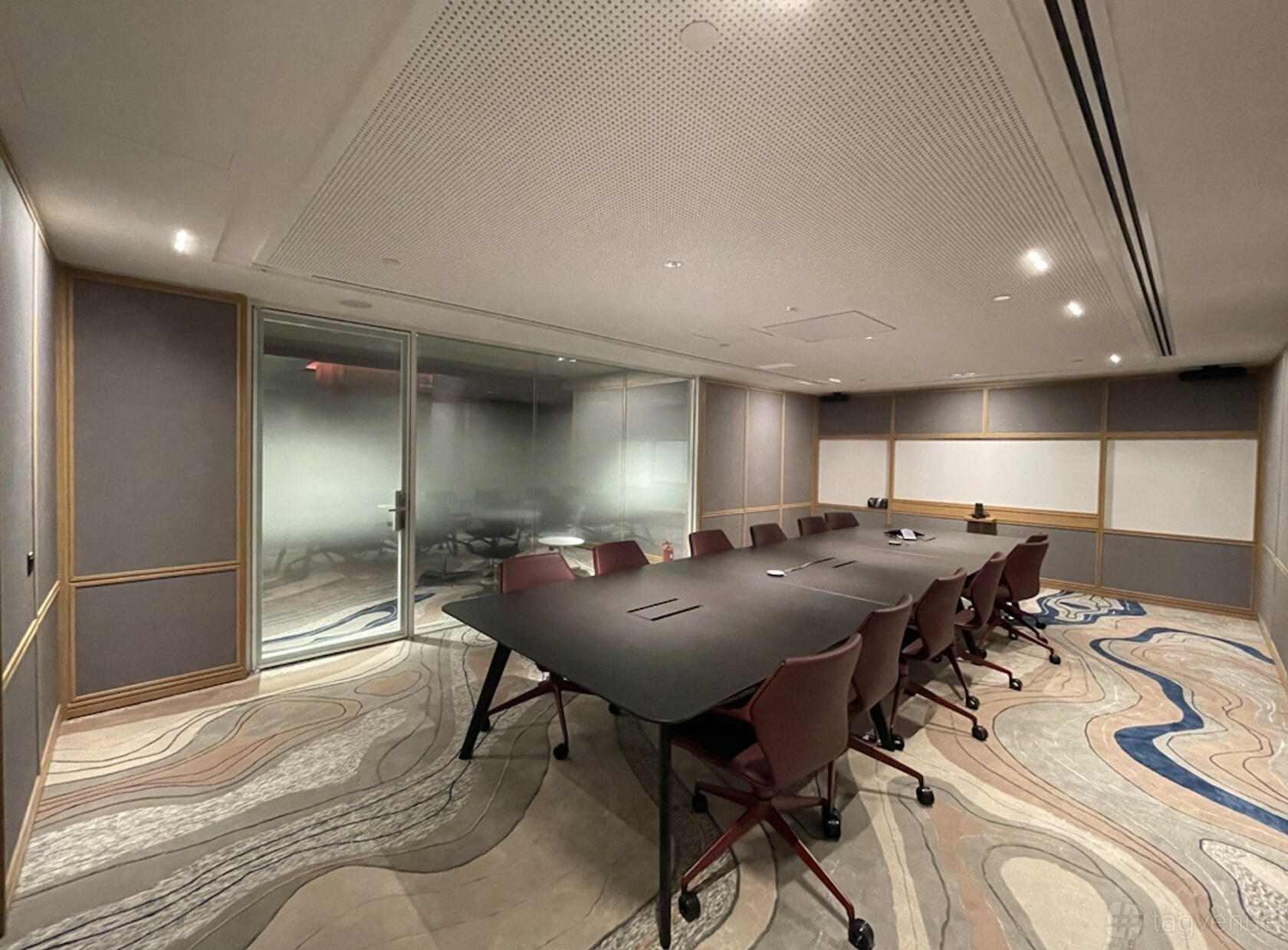 A boardroom with a long conference table, ergonomic chairs, and frosted glass walls at The Work Project 6 Battery Road.