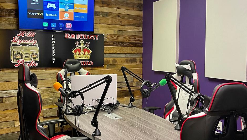 A recording studio with a wooden accent wall, sound panels, and microphones set up around a table at H&M Dynasty Studio.