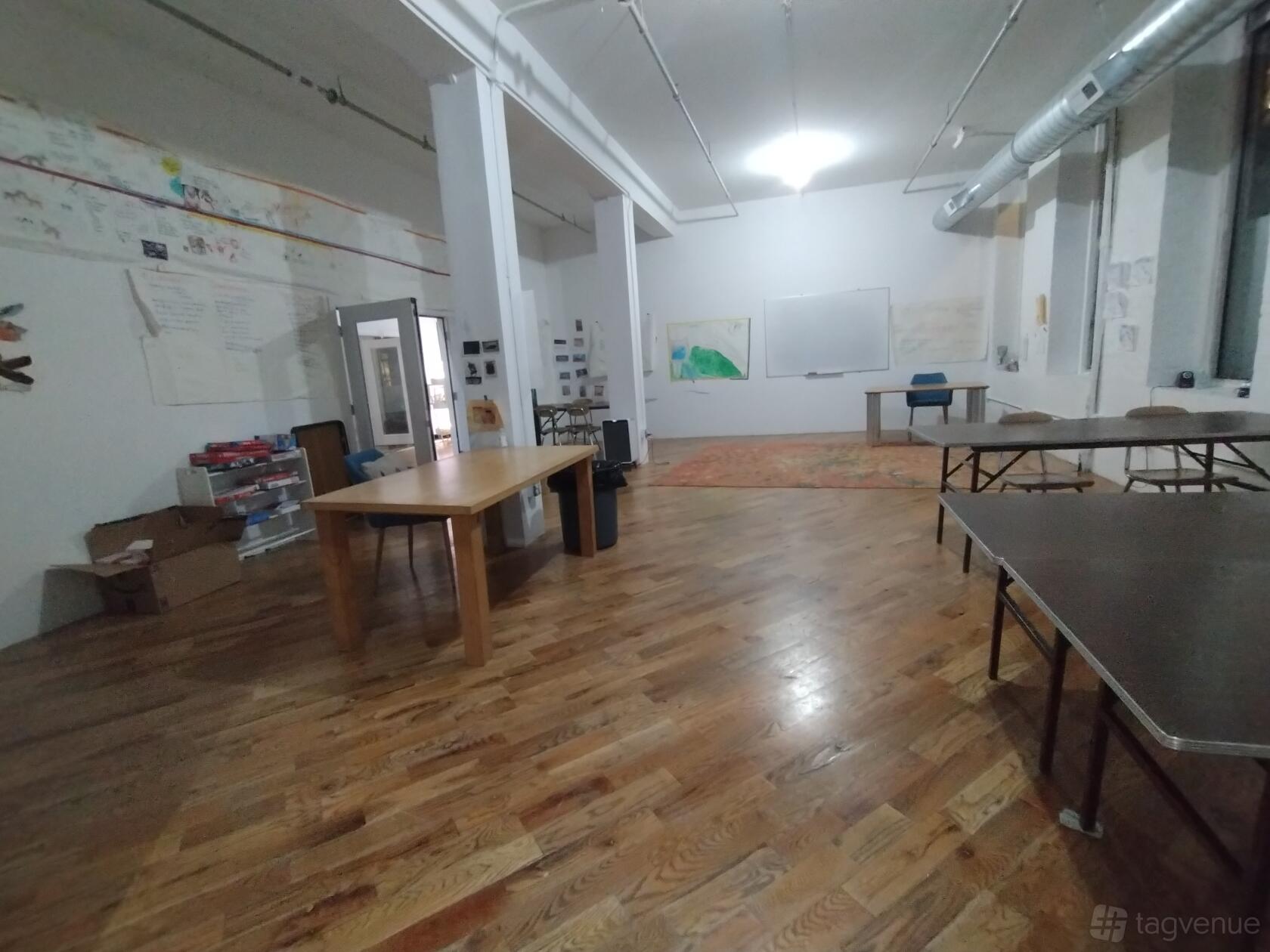 An event venue with hardwood floors, high ceilings, folding tables, and wall art at Espacio de Arte.