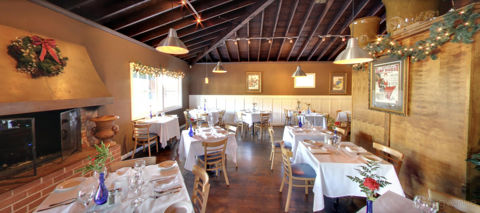 A restaurant with exposed wood beam ceiling, large windows, and tables set with white linens at Parioli Italian Bistro.