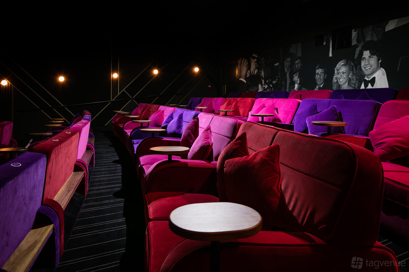 A screening room with plush red and purple armchairs, side tables, and dim wall lighting at Everyman York.