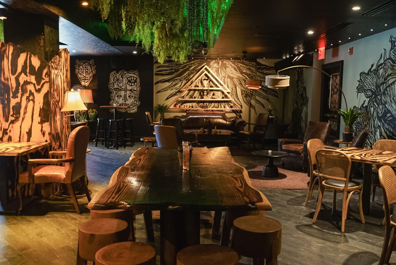 An event space with rustic wooden tables, mural-covered walls, and hanging greenery at Pikio Taco Washington DC.