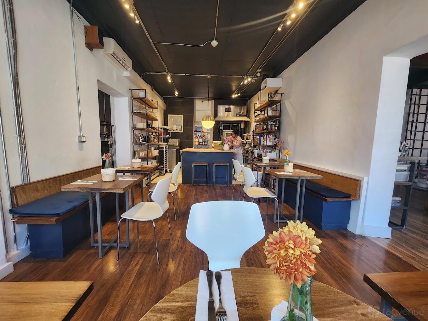 A restaurant with wooden floors, shelving along the walls, small tables, and floral centerpieces at Jezabel's.