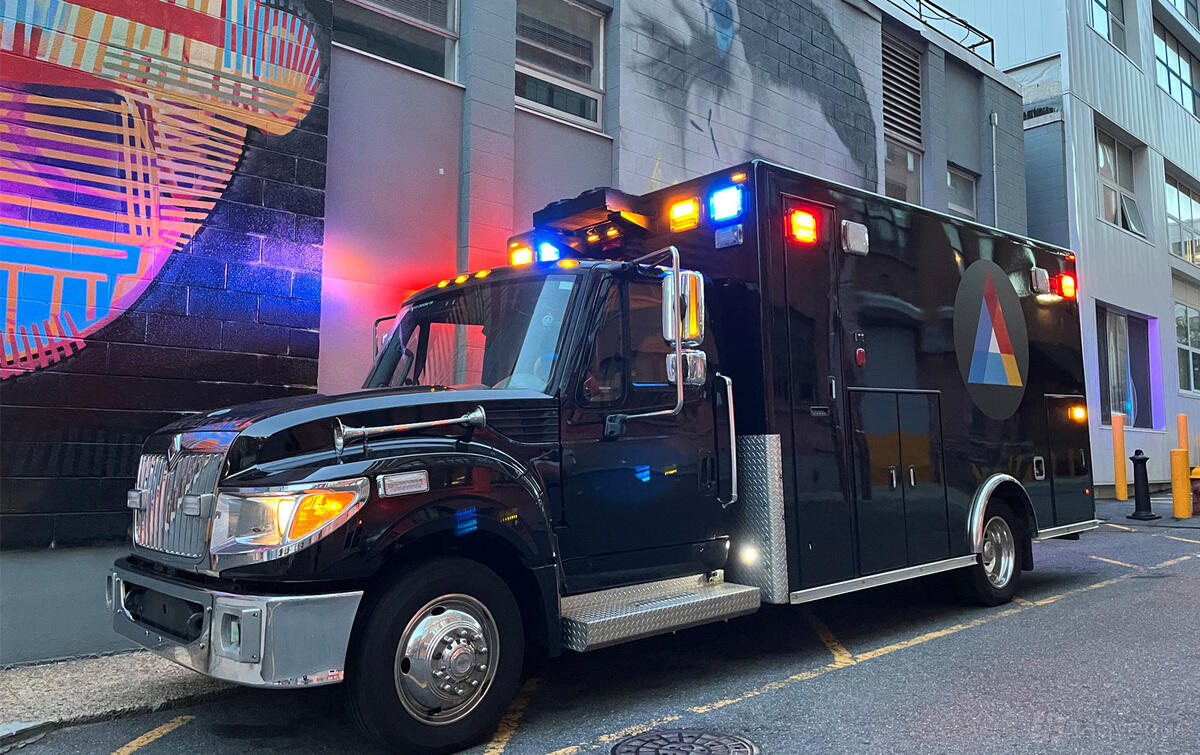 A school with a black mobile studio truck featuring illuminated lights parked beside a mural at S.I.C Film School.